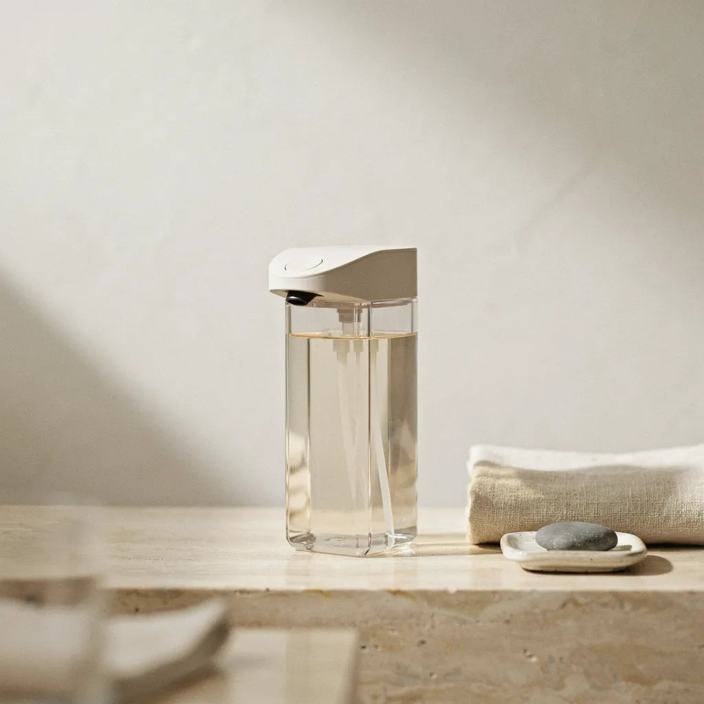 Automatic sensor soap dispenser on a bathroom counter with linen towel