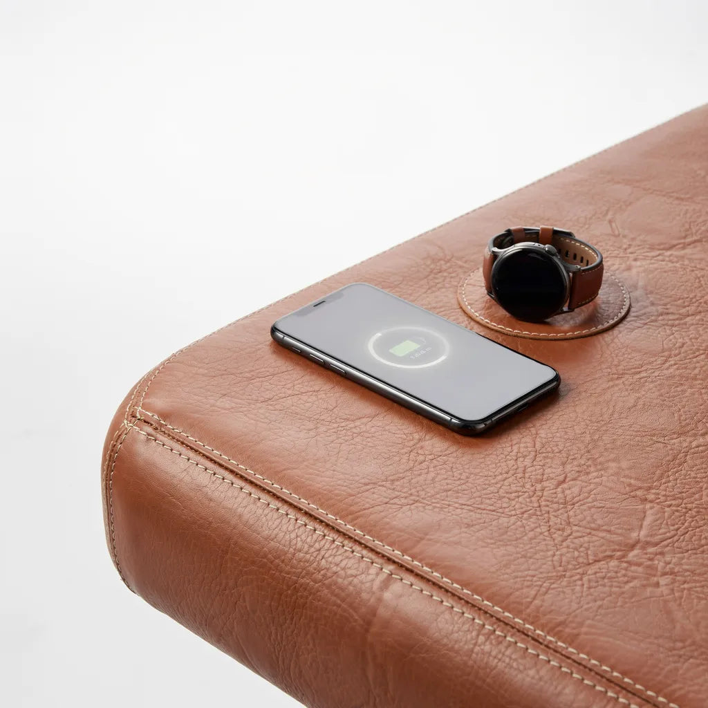 Close-up of phone and watch charging on the leather mat surface